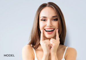 Young female smiling and pointing to cheeks on face esprit® cosmetic surgeons