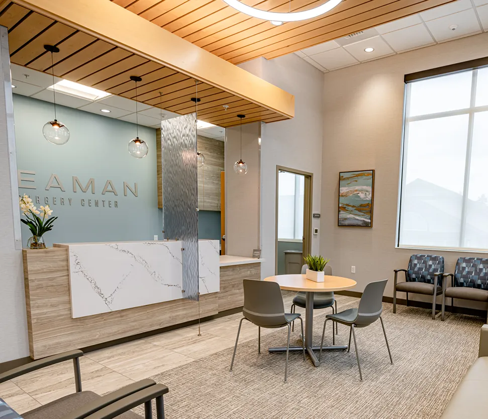 Reception area of a modern clinic with a marble front desk light blue wall and round pendant lights above   esprit® cosmetic surgeons